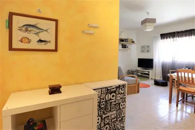 a living room with a yellow wall and a table at Apartamento Palmeira Gale - Beach - Pool - BY BEDZY in Albufeira