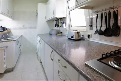 a kitchen with white cabinets and a counter top at Apartamento Palmeira Gale - Beach - Pool - BY BEDZY in Albufeira