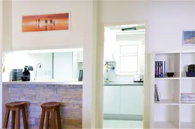 a kitchen with white cabinets and two bar stools at Apartamento Palmeira Gale - Beach - Pool - BY BEDZY in Albufeira