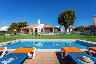 a swimming pool with two chairs and a house at Villa Casa Tina by Villa Plus in Albufeira