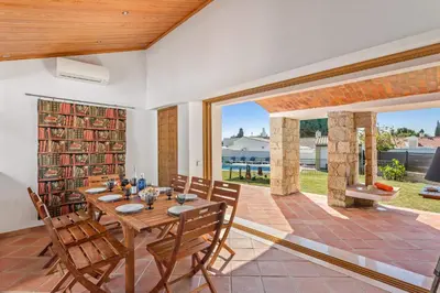 a dining room with a table and chairs and a large window at Villa Casa Tina by Villa Plus in Albufeira