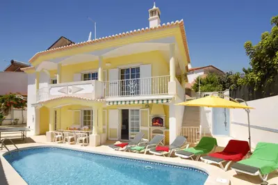 a villa with a swimming pool with chairs and an umbrella at Villa Cubos by Villa Plus in Albufeira
