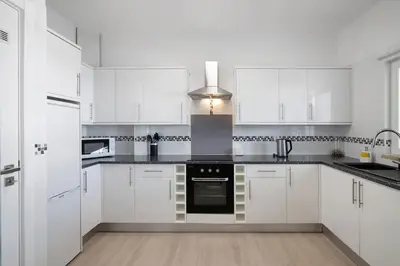 a white kitchen with white cabinets and black appliances at Villa Janeca in Albufeira