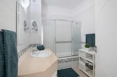 a white bathroom with a sink and a shower at Villa Janeca in Albufeira