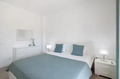 a white bedroom with a bed and two lamps at Villa Janeca in Albufeira