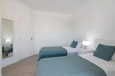 a white room with two beds and a mirror at Villa Janeca in Albufeira