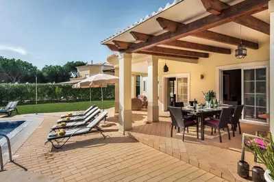 a patio with a table and chairs next to a house at Villa Palm Golfe, fantastic house on Vila Sol course, kids pool, aircon in Quarteira