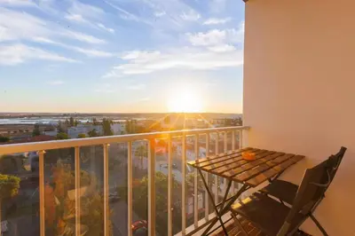 a balcony with a table and chairs and the sunset at Sunset entre a Ria e o Teatro in Faro