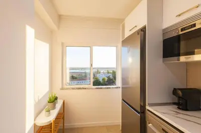 a kitchen with a refrigerator and a table and a window at Sunset entre a Ria e o Teatro in Faro