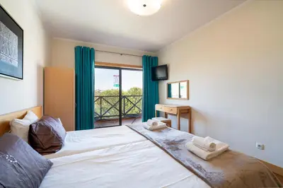 a bedroom with a large white bed with blue curtains at Corcovada in Albufeira