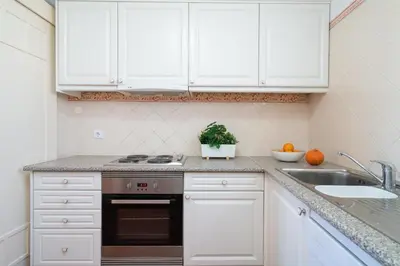 a kitchen with white cabinets and a stove and a sink at Beach villa with ocean view and rooftop cinema in Guia