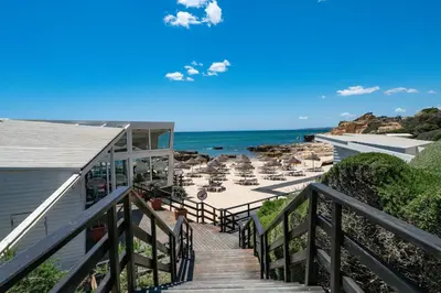 a staircase leading to a beach with chairs and the ocean at Beach villa with ocean view and rooftop cinema in Guia