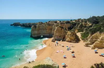 a beach with people and umbrellas and the ocean at Beach villa with ocean view and rooftop cinema in Guia