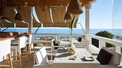 a dining room with tables and chairs and the ocean at Beach villa with ocean view and rooftop cinema in Guia