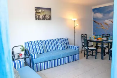 a living room with a blue couch and a table at Apartamento Jardim de Sta Eulália in Albufeira