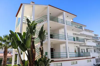 a white building with a palm tree in front of it at Apartamento Jardim de Sta Eulália in Albufeira