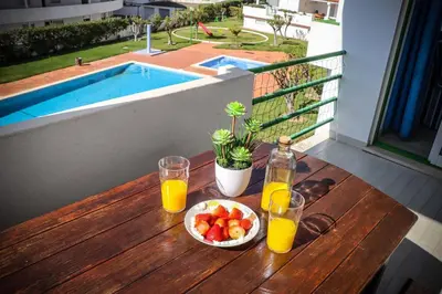 a table with a bowl of fruit and two glasses of orange juice at Apartamento Jardim de Sta Eulália in Albufeira