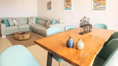 a living room with a wooden table and blue chairs at House J São Rafael - By Bedzy in Albufeira