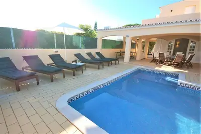 a swimming pool with chairs next to a house at Qta do Eucalipto Villa in Faro