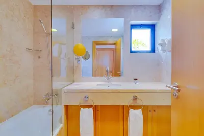 a bathroom with a sink and a shower with a mirror at AL - Apartamento Vila Sol F5 D in Vilamoura