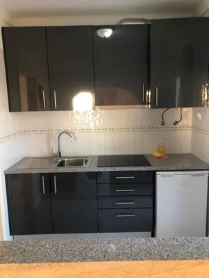 a kitchen with black cabinets and a sink at Debimar Apartamentos in Albufeira