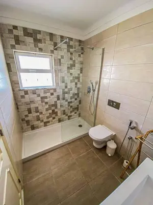 a bathroom with a shower and a toilet and a window at Debimar Apartamentos in Albufeira