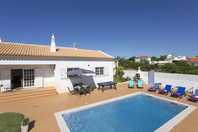 a backyard with a swimming pool and chairs and a house at Villa Goia by Villa Plus in Olhos de Água