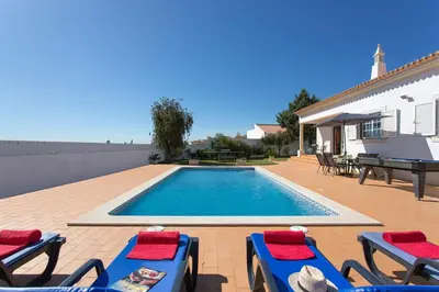 a patio with a table and chairs and an umbrella at Villa Goia by Villa Plus in Olhos de Água