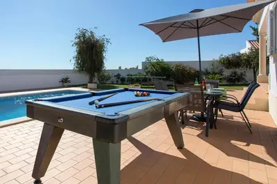a pool table sitting on a patio with an umbrella at Villa Goia by Villa Plus in Olhos de Água