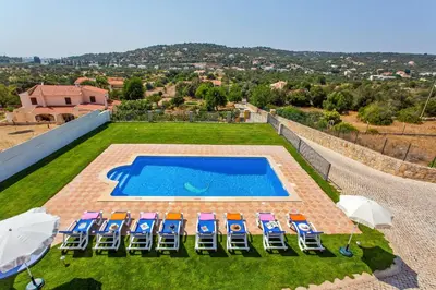 a group of lawn chairs and a swimming pool at Villa Ribeiro Tomas by Villa Plus in Loulé
