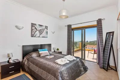 a bedroom with a large bed and a balcony at Villa Ribeiro Tomas by Villa Plus in Loulé