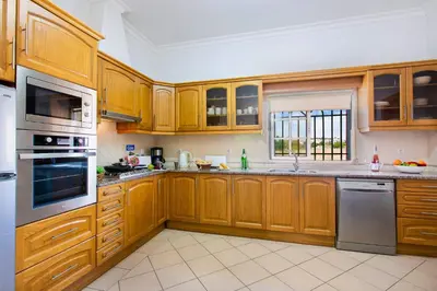 a kitchen with wooden cabinets and stainless steel appliances at Villa Arvela by Villa Plus in Galé