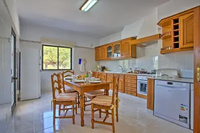 a kitchen with a wooden table and chairs in it at Villa Candida by Villa Plus in Vale do Lobo