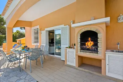 a patio with a fireplace with a table and chairs at Villa Casa do Mel by Villa Plus in Loulé