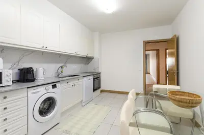 a kitchen with a washing machine and a table and chairs at Miral 2 - Beach front apartment with pool in Quarteira