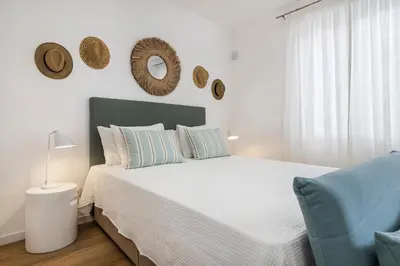 a bedroom with a white bed and a blue chair at RG Studio in Faro