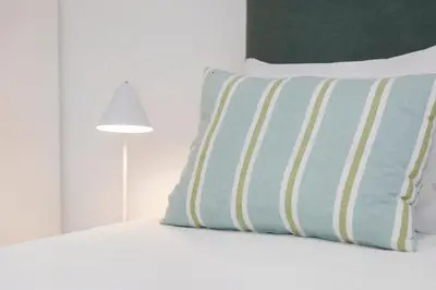a bed with a blue and yellow pillow and a lamp at RG Studio in Faro