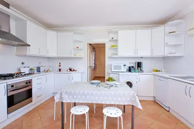a kitchen with white cabinets and a table with stools at Villa Celia by Villa Plus in Olhos de Água