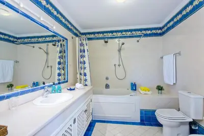 a bathroom with a tub and a sink and a toilet at Villa Celia by Villa Plus in Olhos de Água