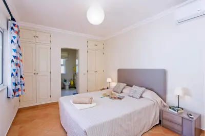 a white bedroom with a large bed with white sheets at Villa Celia by Villa Plus in Olhos de Água