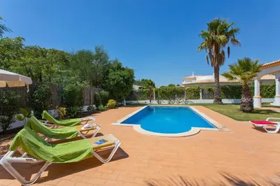 a swimming pool with two lawn chairs next to a house at Villa Celia by Villa Plus in Olhos de Água