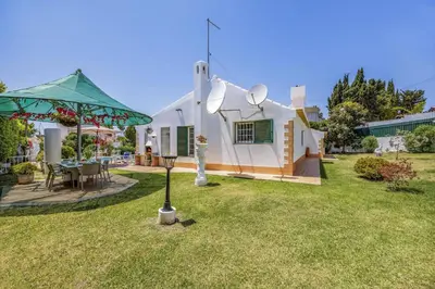 a white house with a green umbrella in the yard at Villa Eliza by Villa Plus in Albufeira