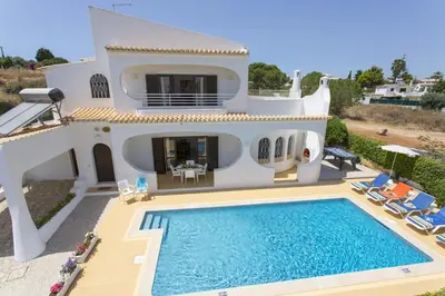 a villa with a swimming pool in front of a house at Villa Medeira by Villa Plus in Albufeira