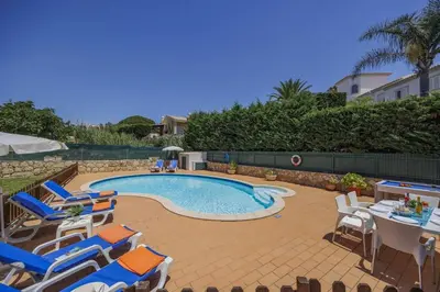 a swimming pool with lounge chairs and a table at Villa Praia by Villa Plus in Galé