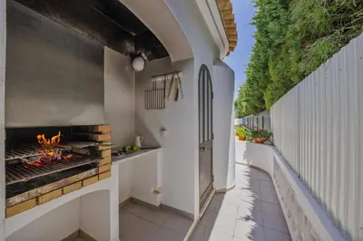 an outdoor kitchen with an outdoor grill on a patio at Villa Praia by Villa Plus in Galé