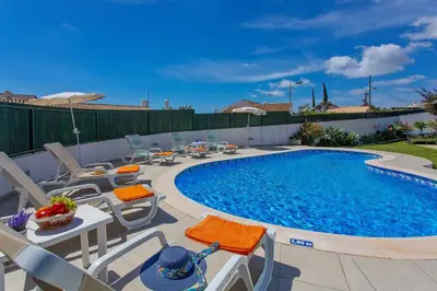 a swimming pool with chairs and a table next to it at Villa Rocchi by Villa Plus in Albufeira