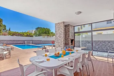 a dining room with a table and chairs and a pool at Villa Sea Star by Villa Plus in Albufeira