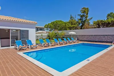 a swimming pool with blue lounge chairs and a house at Villa Sea Star by Villa Plus in Albufeira