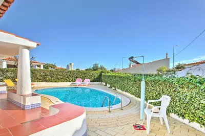 a swimming pool with two chairs and a table at Villa Vitor by Villa Plus in Albufeira