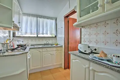 a kitchen with white cabinets and a sink and a window at Villa Vitor by Villa Plus in Albufeira
